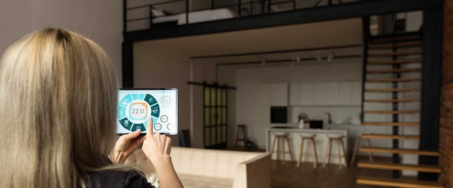 Frau steuert Smart Home per Tablet im Wohnzimmer; 22 °C eingestellt.