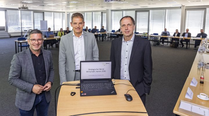 Drei Männer am Rednerpult, Laptop zeigt: ‚Hamm 2030‘; Teilnehmende im Hintergrund.